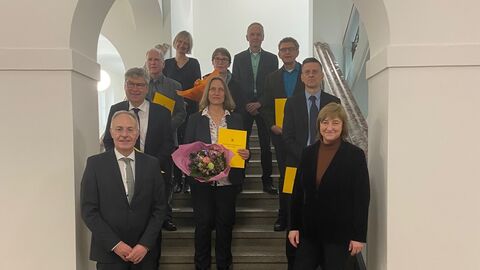 Die ernannten Richterinnen und Richter stehen gemeinsam mit Justizministerin Kühne-Hörmann in einem Torbogen, nach hinten auf Stufen verteilt und lächeln in die Kamera.