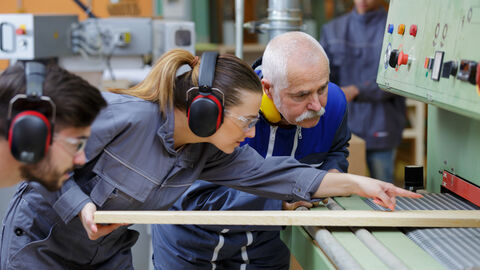 Mehrere Personen arbeiten an einer Maschine in der Holzverarbeitung