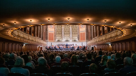 Publikum blickt auf Bühne mit Orchester