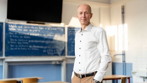 Ein Mann steht vor einer Schultafel.