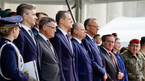 Ministerpräsident Rhein, Bundeskanzler Merz, Verteidiungsminister Pistorius und weitere Personen stehen zusammen.