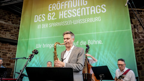 Das Hessentagspublikum bei der Eröffnung Eine Band spielt vor einem bunten Hintergrund