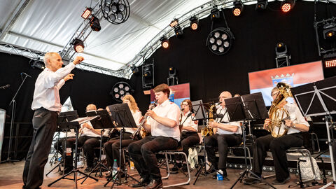 Hessentag 2025 Bundeswehr Mehrere Personen stehen und sitzen auf einer Bühne und spielen Instrumente.