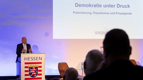 Blick auf die Bühne des Herbstgesprächs, auf der Innenminister Poseck am Rednerpult steht und spricht.