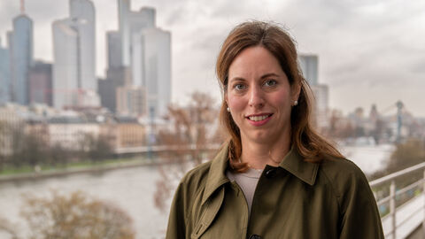 Eine Frau steht auf einer Brücke. Im Hintergrund stehen Hochhäuser.