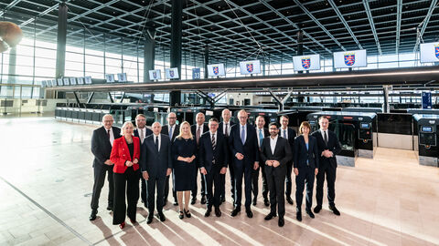 Eine Gruppe von 14 Personen stehen in einer Halle, dem neuen Terminal am Frankfurter Flughafen.